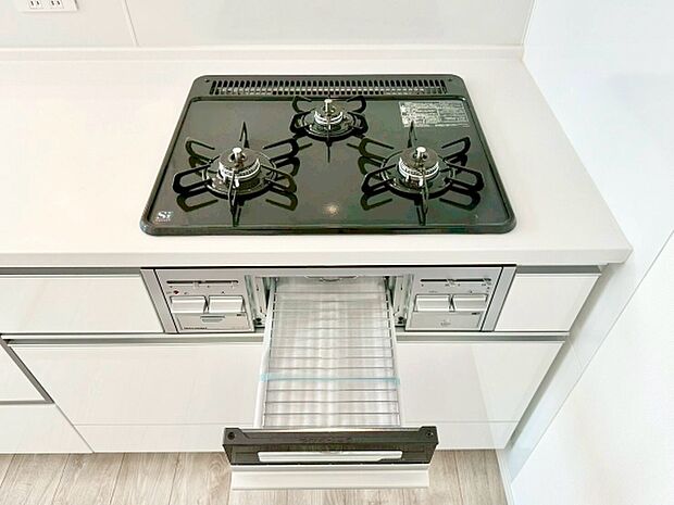 シンプルなデザインで清潔感のあるキッチンです。三口コンロは調理の幅が広がります。収納スペースが使いやすい配置になっています。グリル付きで料理のバリエーションも楽しめます。