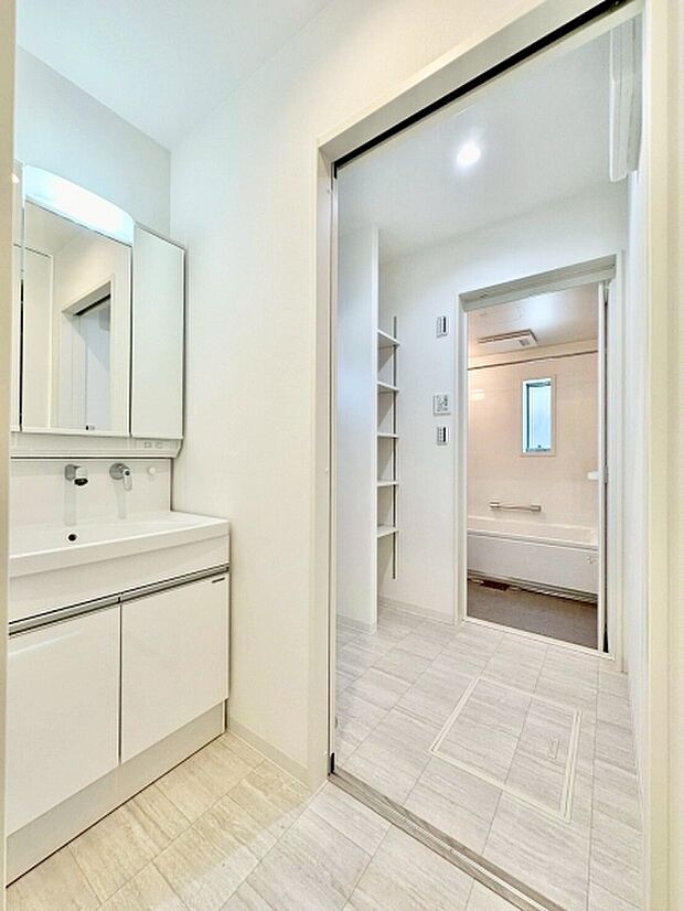 白を基調とした洗面台・洗面所が清潔感を感じさせます。大きな鏡が印象的で空間が明るく見えます。収納スペースも確保され使い勝手に配慮されています。浴室への動線がスムーズで日々の支度に便利です。