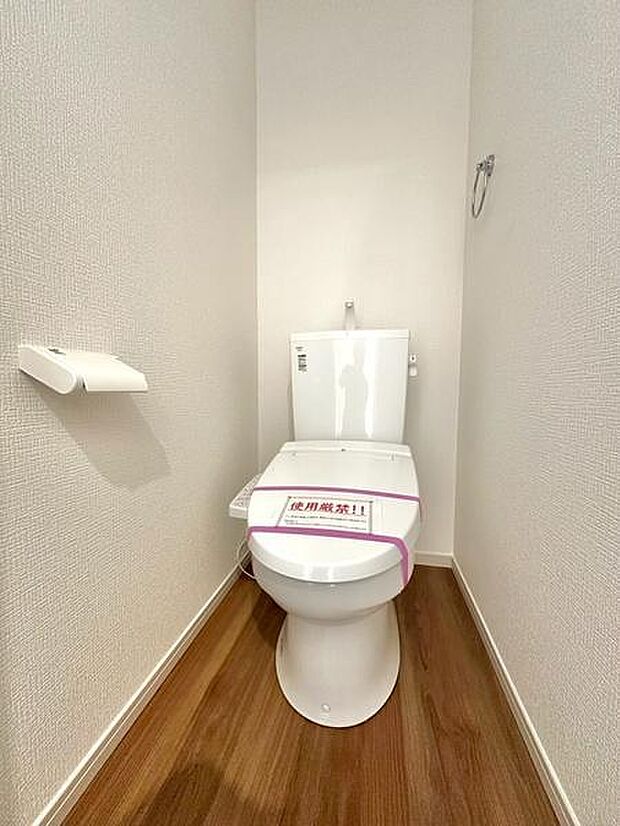 トイレは明るく清潔感のある空間になっています。床材には木目が採用されすっきりとした印象です。壁面はシンプルなデザインでお手入れもしやすそうです。ペーパーホルダーも設置されています。