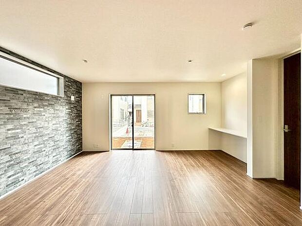 (LDK18.25帖)大きな窓から自然光が差し込み明るさが際立ちます。スタイリッシュな石目調のアクセントウォールが魅力的です。床材の風合いが温かみを感じさせます。