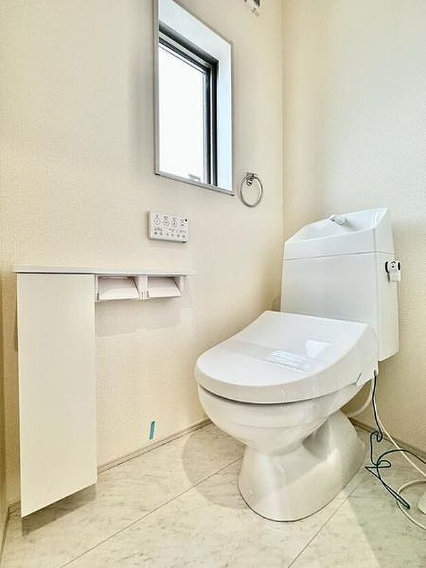 明るい空間に設置されたトイレは清潔感を演出しています。窓があるため自然光が取り入れられ換気も良好です。ペーパーホルダーや収納も備わっており使い勝手に配慮された造りです。