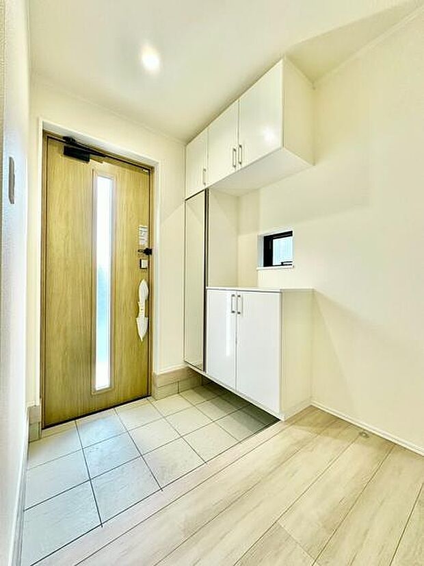 明るく清潔感のある玄関です。豊富な収納スペースが備わっておりすっきりとした印象です。木目調のドアが温かみを感じさせます。床材の切り替えが空間にアクセントを加えています。