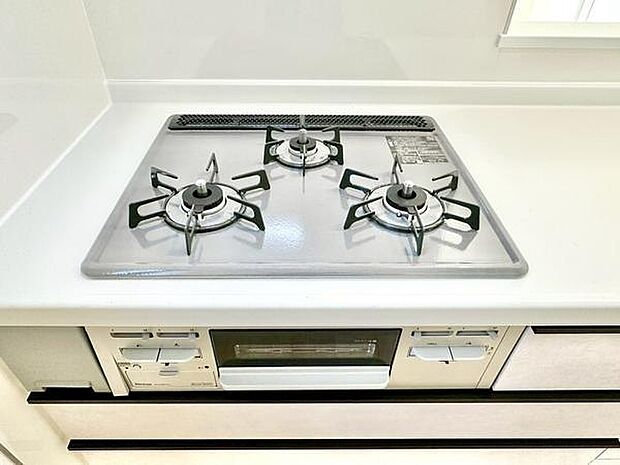 三口コンロが設置されており調理スペースも広く確保されています。白を基調とした清潔感のあるキッチンです。ガスコンロの下にはグリルも備わっています。シンプルなデザインで使いやすい印象です。