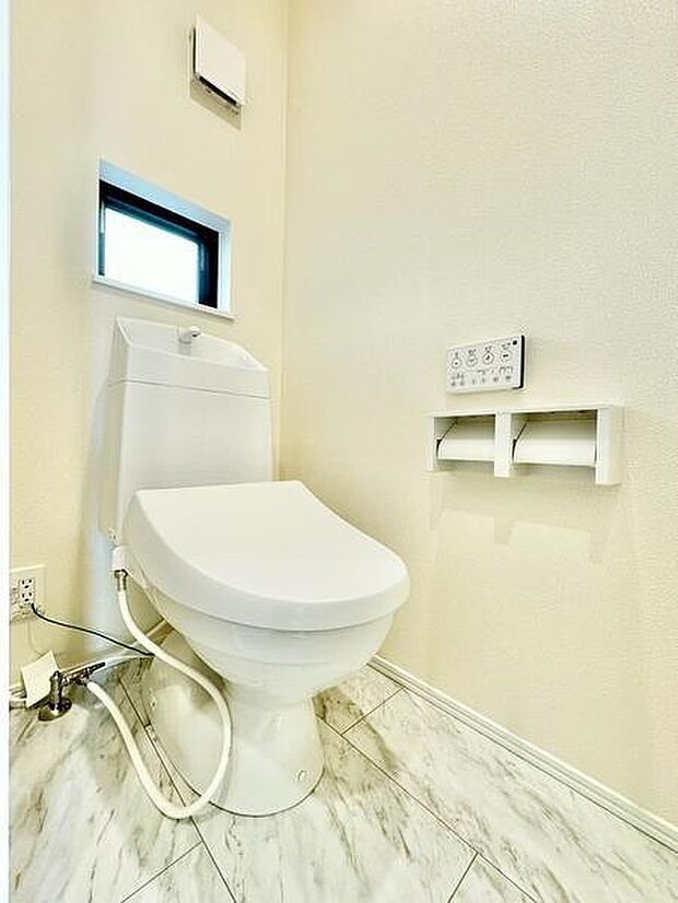 明るい色調のトイレ空間が広がります。壁付けのリモコン操作パネルが設置されています。窓があり通気性にも配慮されています。床はお手入れしやすい素材が採用されています。