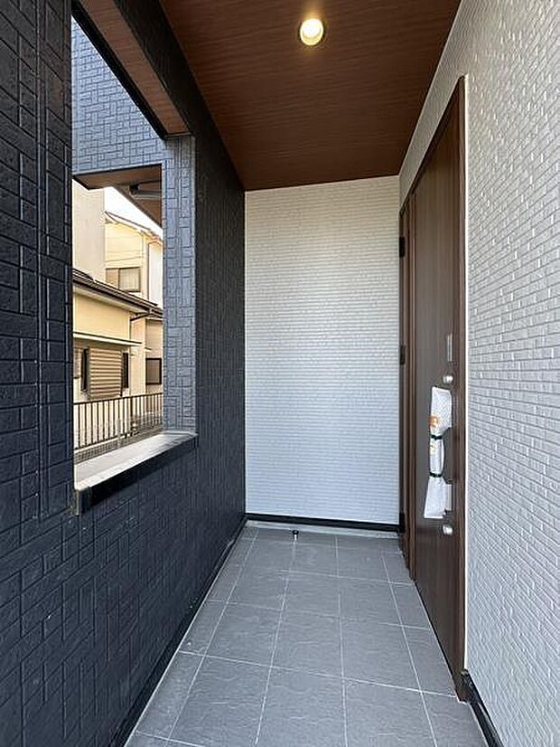 玄関スペースはタイル張りで手入れがしやすい造りです。ブラックとホワイトの壁面が印象的なコントラストを演出しています。窓付きで採光も確保されており落ち着いた雰囲気が感じられます。