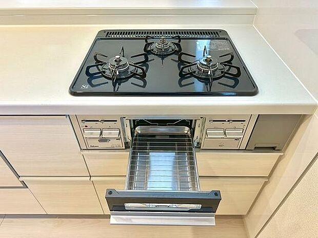 三口コンロが設置されておりさまざまな料理に対応しやすいキッチンです。グリルが付いているため調理の幅が広がります。フラットなワークトップでお手入れも簡単です。