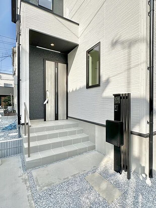 落ち着いた色合いの玄関が住まいの印象を引き締めます。階段で高低差を活かしたアプローチが特徴的です。外壁の素材感もアクセントになりスタイリッシュな仕上がりです。