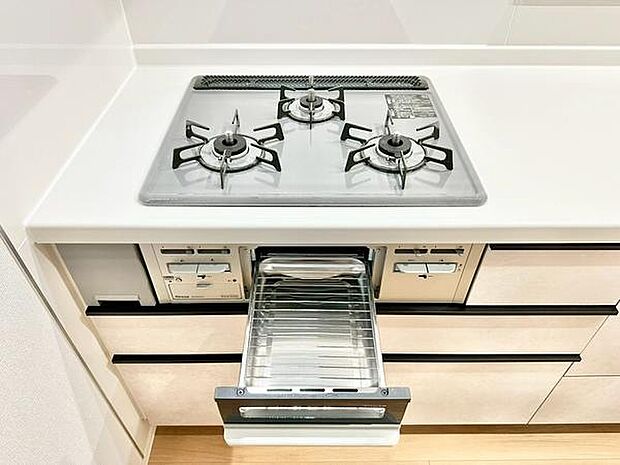 すっきりとしたデザインのキッチンは使い勝手を意識したレイアウトが魅力です。三口コンロとグリル付きで調理もスムーズに進みます。シンプルながらも収納力のある引き出しもポイントです。