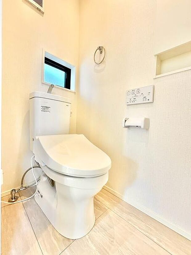 明るい色合いの壁と床がトイレ空間をすっきりと見せてくれます。小窓から自然光が入り換気にも配慮されています。壁に埋め込み収納スペースが設けられている点も特徴です。