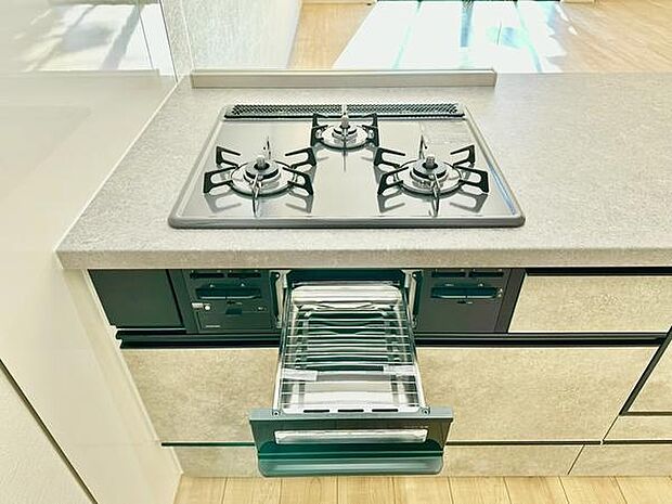 三口コンロを備えたキッチンです。グリル付きで調理の幅が広がります。シンプルなデザインが使いやすさを感じさせます。カウンターも広くお手入れがしやすいです。