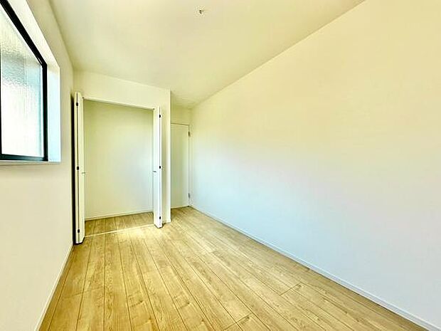 (洋室5.6帖)シンプルな白い壁で明るさを感じられます。クローゼット付きで収納スペースも確保されています。窓から自然光が差し込み日中も快適に過ごせます。