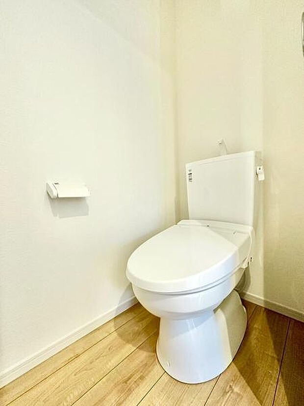 明るく清潔感のあるトイレです。床材の色合いがナチュラルな雰囲気を演出しています。壁や床に余計な装飾がなくシンプルで落ち着いた空間です。手元にペーパーホルダーが配置されていて便利です。