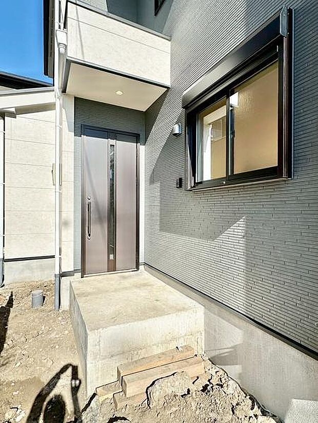 スタイリッシュな玄関ドアが印象的な外観です。モダンな外壁デザインが目を引きます。明るい日差しが差し込み開放感を感じられる玄関まわりです。新築ならではの清潔感も魅力です。