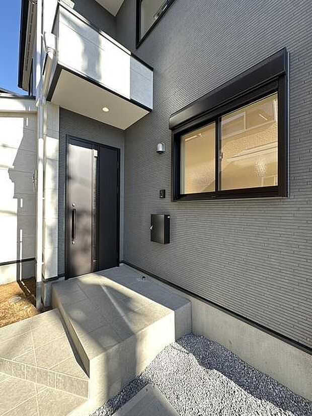 スタイリッシュな玄関ドアが印象的な外観です。モダンな外壁デザインが目を引きます。明るい日差しが差し込み開放感を感じられる玄関まわりです。新築ならではの清潔感も魅力です。