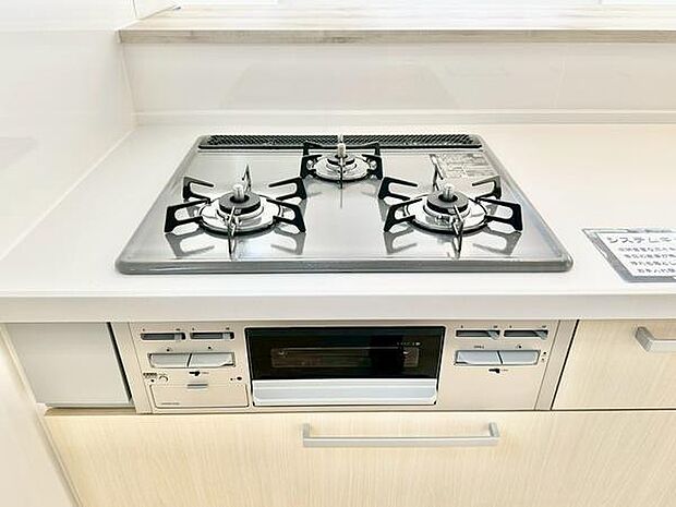 シンプルで清潔感のあるキッチンです。使いやすいガスコンロが設置されています。引き出しや収納スペースも確保されています。手入れがしやすいデザインです。調理が快適にできる環境です。