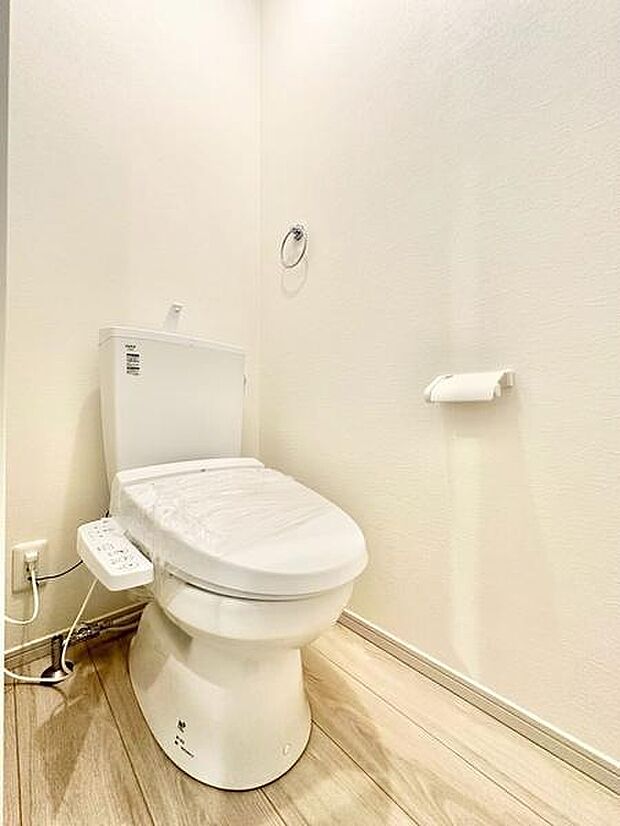 明るく清潔感のあるトイレ空間です。温水洗浄便座が設置されています。シンプルな内装でお手入れもしやすい設計です。床材と壁紙の色合いが調和しています。