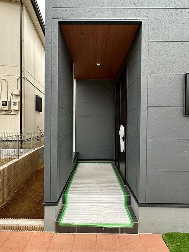 スタイリッシュな外観デザインが印象的な玄関です。奥行きのあるアプローチが特徴でさりげなくプライバシーにも配慮されています。天井にはダウンライトが設けられ夜間も安心して利用できます。
