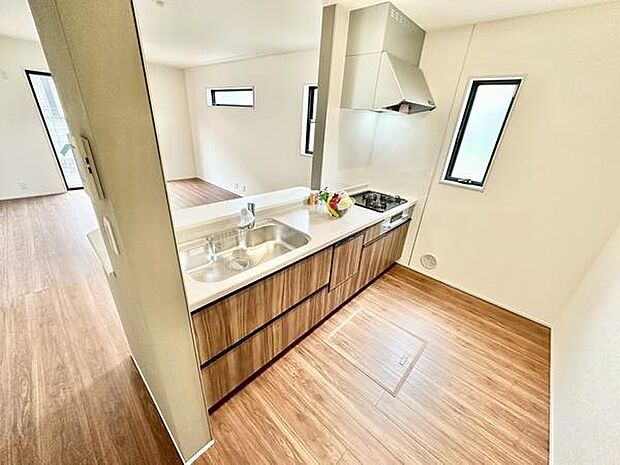 木目調のキャビネットが空間に温かみを与えています。窓が多く明るさがしっかり確保されています。カウンターが広く作業スペースが十分に取られています。清潔感のある内装が特徴的です。