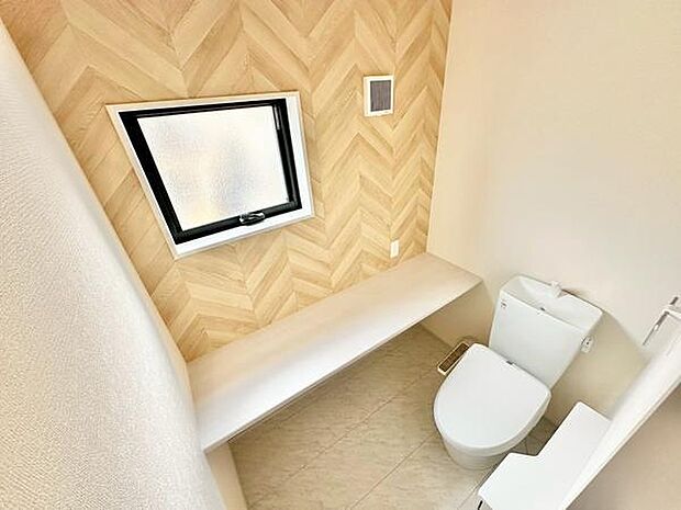 ナチュラルな木目調の壁が印象的なトイレです。窓が設置されており自然光が差し込む室内です。換気や採光に配慮された空間となっています。シンプルなデザインで手入れもしやすいです。