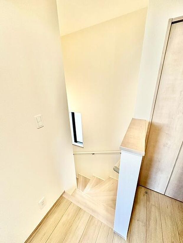 明るい色合いのフローリングが空間全体を爽やかに演出しています。階段部分には窓が設けられており自然光が差し込みます。手すりや壁面の仕上げもシンプルで清潔感があります。全体的に洗練されたデザインです。