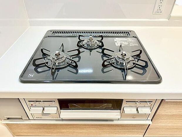 清潔感のあるキッチンに設置された三口コンロです。キッチンには使いやすいグリルも備え付けられておりさまざまな調理が可能です。天板がフラットなので日常の手入れも簡単に行えます。
