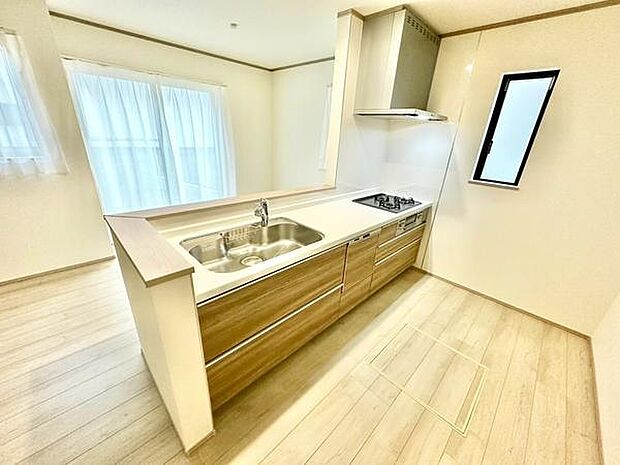ナチュラルな木目調のデザインが空間に調和しています。ワイドなカウンターが便利です。二面採光で明るいキッチンです。換気がしやすい窓付きのレイアウトです。収納スペースも確保されています。