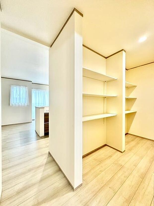 開放感のあるキッチンと隣接した収納スペースが魅力です。可動式の棚で整理整頓もスムーズです。明るい床色で空間全体が広く感じられます。動線がシンプルなので移動も快適です。収納力がうれしいレイアウトです。