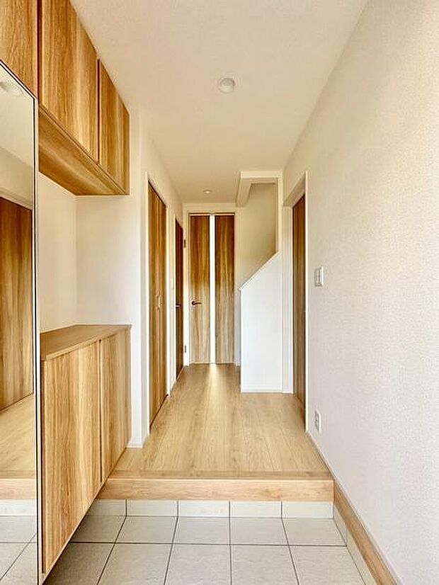 玄関のすっきりとした空間が印象的です。木目調の収納がやわらかな雰囲気を演出しています。明るい色合いで圧迫感が少なく使いやすさが感じられます。玄関から見える廊下もスマートな造りです。