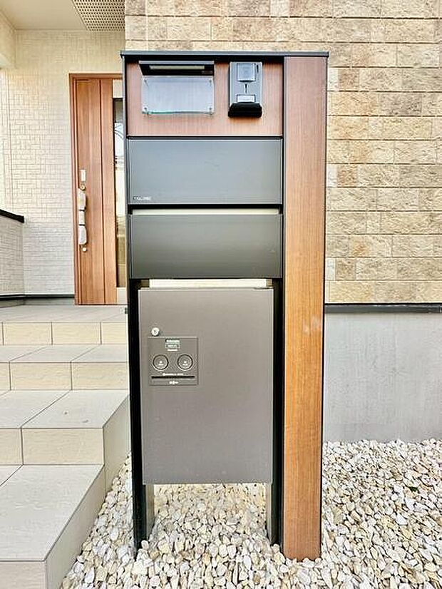 シンプルなデザインの宅配ボックスが設置された玄関まわりです。郵便受けと宅配ボックスが一体型で便利です。木目調フレームが外観に調和しています。使いやすさと機能性が感じられる設備です。