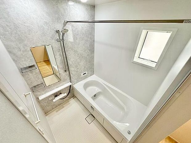 シンプルな内装と明るい照明が印象的なバスルーム。広々とした浴槽でゆったりくつろげ、便利な棚やシャワー設備、窓付きで換気も良好な清潔感ある空間です。