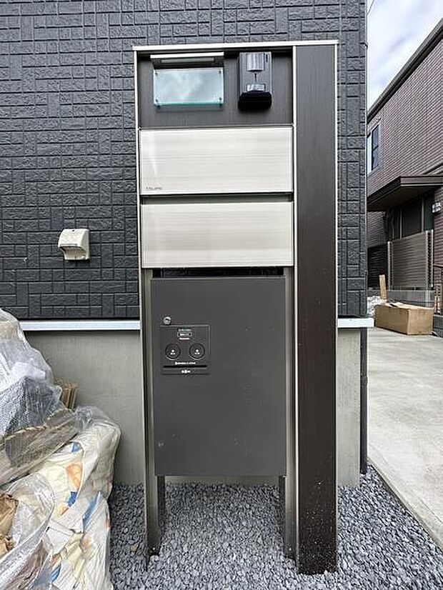 スタイリッシュなデザインが印象的な宅配ボックスで、ダーク系の外壁とも調和しやすい色合いです。表札スペースやポスト、宅配ボックスが一体化されており、玄関まわりがすっきりとまとまっています。