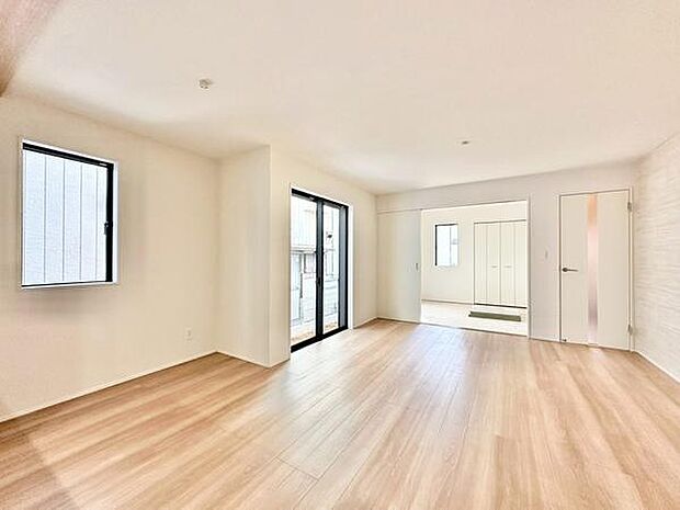 【16.37帖】大型の窓から光が差し込む明るいリビングです。白を基調とした内装が空間を広く見せ、床材のナチュラルな色味が落ち着いた雰囲気を演出しています。