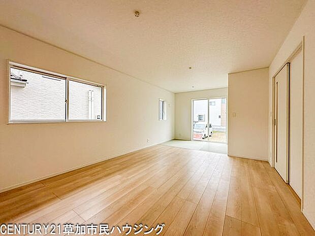 【15帖】大きな窓から光が差し込む明るく開放感のあるリビングです。シンプルな内装でインテリアの自由度も高く使いやすい空間です。床材のナチュラルな色合いが温かみを演出しています。