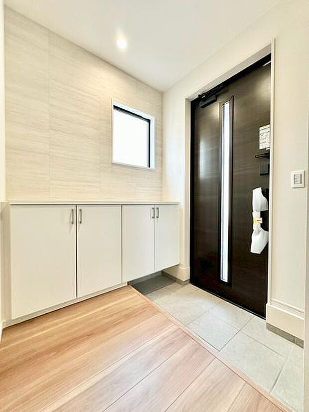 玄関は明るく開放的な空間で白を基調とした収納がすっきりとした印象です。シンプルなデザインの玄関ドアがモダンな雰囲気を演出しています。窓からの自然光もしっかりと入り清潔感のある玄関です。