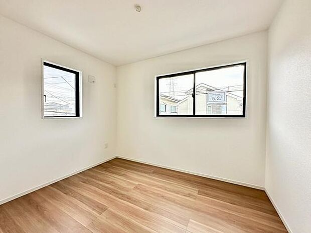 【5.2帖洋室】シンプルな内装が印象的なリビングです。二面に窓があり室内が明るく開放的な空間となっています。ホワイトと木目のコントラストが落ち着いた雰囲気を演出しています。