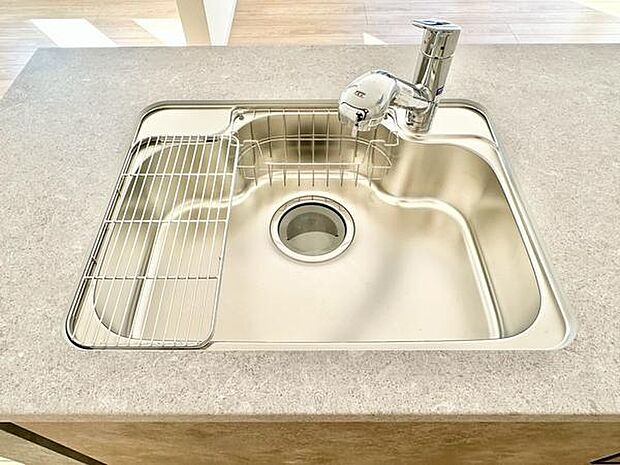 シンプルで手入れがしやすいデザインのシンクです。蛇口もスマートな形状で日々の作業が快適に行えます。水切りラックも付属しており機能性に配慮されています。清潔感のあるキッチン空間です。