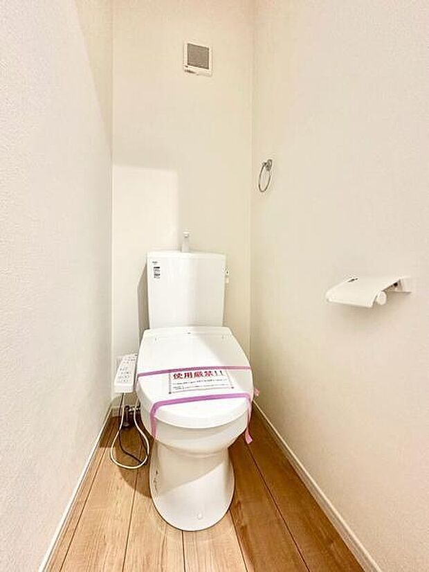 明るく清潔感のあるトイレです。白を基調としシンプルな内装が印象的です。床は木目調で温かみを感じられます。機能的なレイアウトで使いやすい空間となっています。ペーパーホルダーも設置されています。