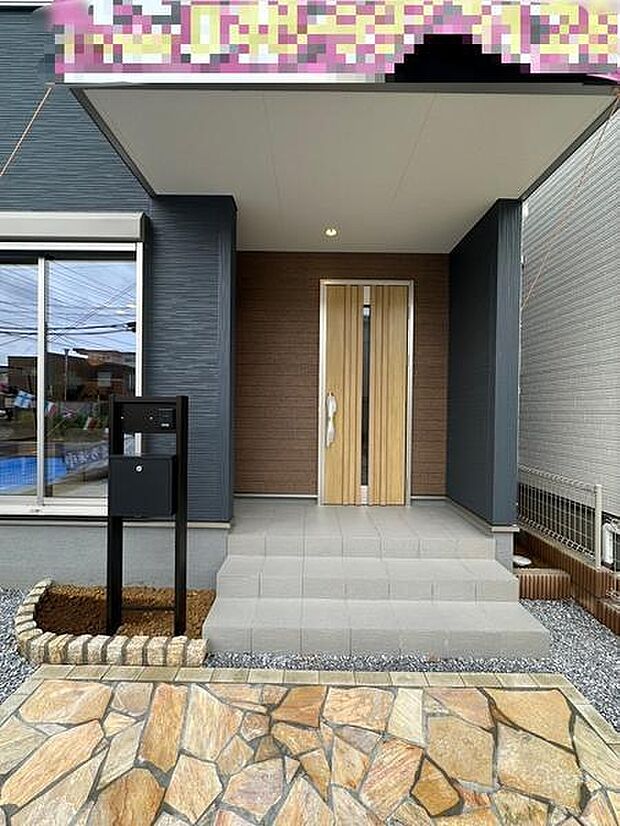 グレーとブラウンの外観カラーが調和した上品な玄関。屋根が設けられているため、雨や日差しを避けながらゆったりと出入りできます。