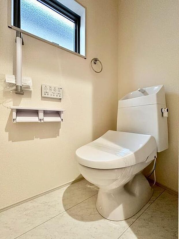 窓付きで換気のしやすいトイレ。トイレットペーパーホルダーを2連で設置し、手すりも備えた使い勝手の良い空間です。