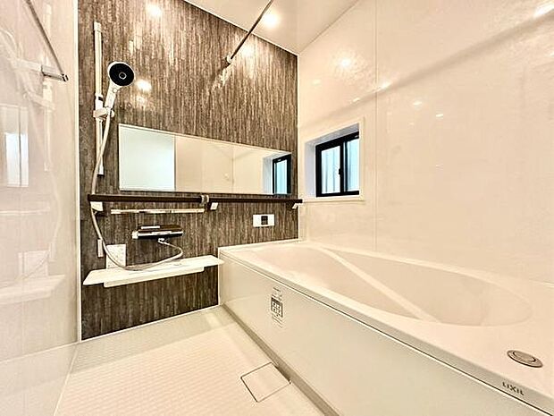 スタイリッシュな壁面デザインが印象的なバスルームです。大型のミラーが空間に広がりを演出しています。便利な棚と窓付きで快適さが感じられます。手入れがしやすい仕様となっています。