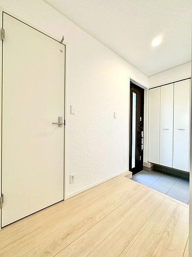 玄関スペースは明るく開放的な印象で、白を基調としたデザインが清潔感を演出しています。収納も備わっており、整理整頓がしやすい設計です。