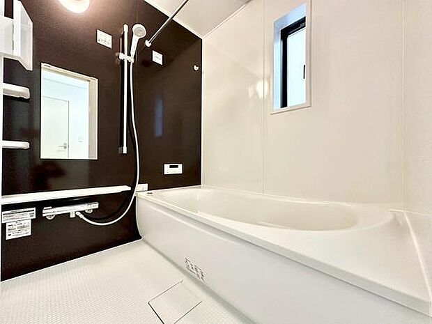 清潔感のあるホワイトとアクセントパネルが調和したバス空間です。浴槽はゆったりとした設計で使いやすい手すりやミラーも備えています。窓が設けられており換気や採光にも配慮されています。