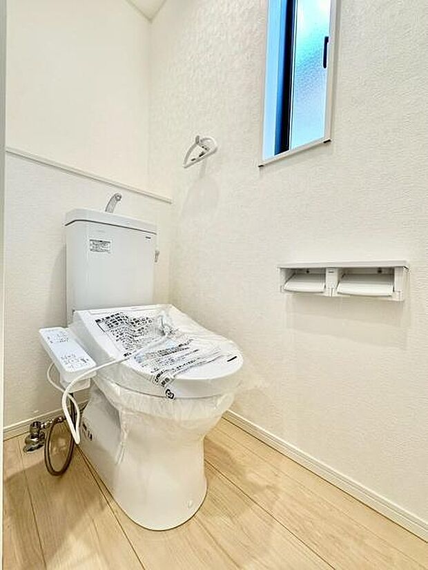 フローリングが明るく清潔感のあるトイレです。窓が設けられており自然光が取り入れられる空間となっています。手すりやペーパーホルダーなど実用的な設備も整っています。快適に使用できる環境が整っています。