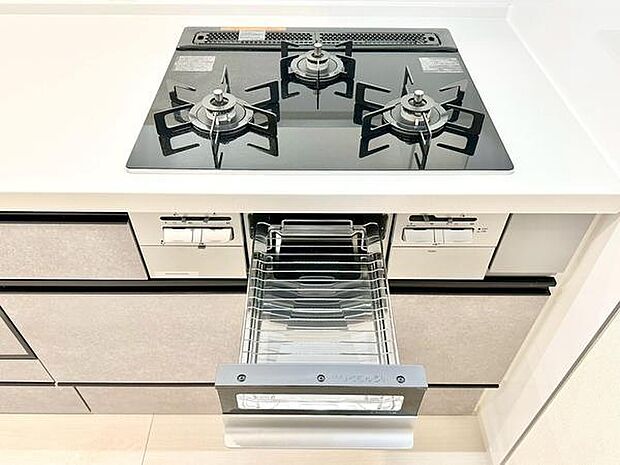 シンプルで洗練されたデザインのキッチンです。3口コンロを採用しており調理の幅が広がります。グリル付きで多彩な料理に対応可能です。手入れもしやすい天板仕様となっています。