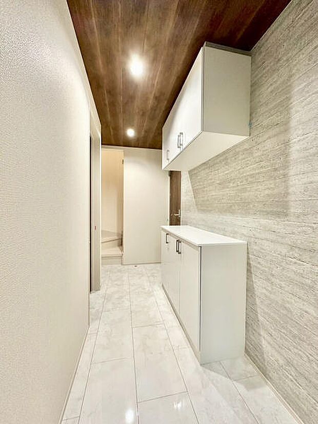 シンプルで洗練された玄関が印象的です。天井の木目調が空間のアクセントとなり、温かみのある雰囲気を演出。収納スペースも豊富に備わっており整理整頓がしやすく、明るい照明が玄関をやさしく照らします。