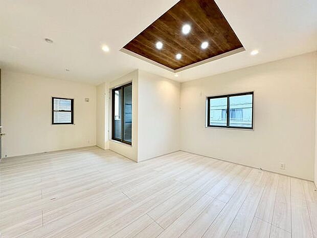 【約17帖】明るい色合いのフローリングが空間を開放的に演出します。天井のアクセントパネルとダウンライトが特徴的です。大きな窓から自然光が差し込み室内がやさしく照らされます。