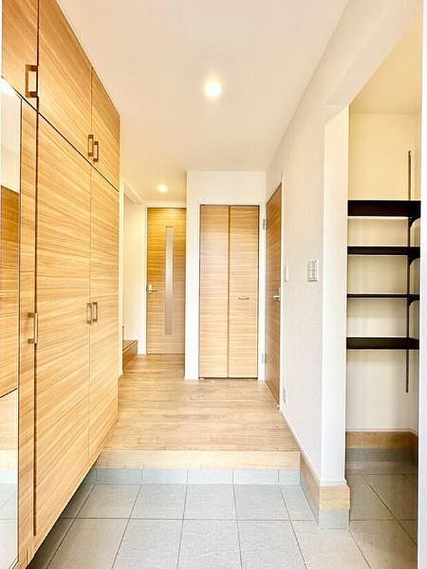 明るく開放感のある玄関です。収納スペースが充実しており整理整頓もしやすい設計です。シンプルなデザインが空間にすっきりとした印象を与えます。木目調の仕上げが温かみをプラスしています。