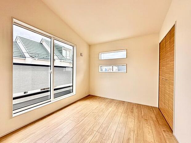 大きな窓から光が差し込む明るい空間です。木目調のフローリングが温かみを演出します。二つの小窓もポイントで通風もしっかり確保されています。収納スペースも備えておりすっきりとした印象の寝室です。