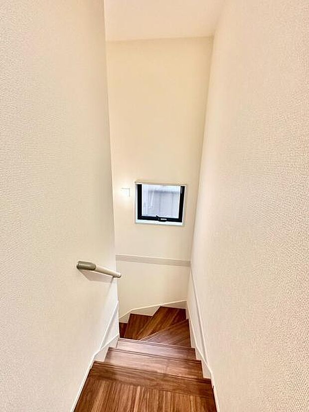 階段部分に窓が設置されており自然光が差し込む明るい空間です。手すり付きで上り下りも快適に利用できます。壁や床の色合いがシンプルで清潔感のある仕上がりです。