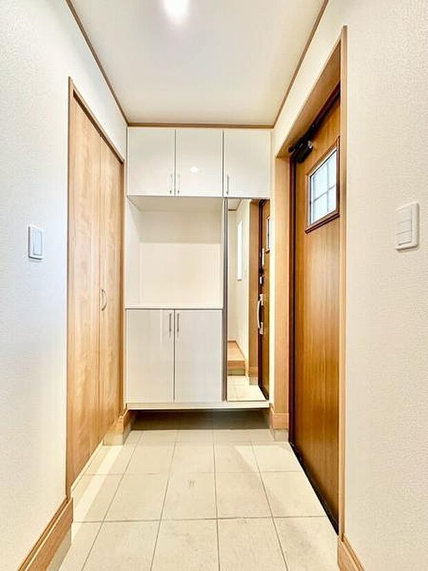 明るい印象の玄関で木目の扉と白を基調とした収納が調和しています。収納スペースが充実しておりすっきりとした空間が保てます。